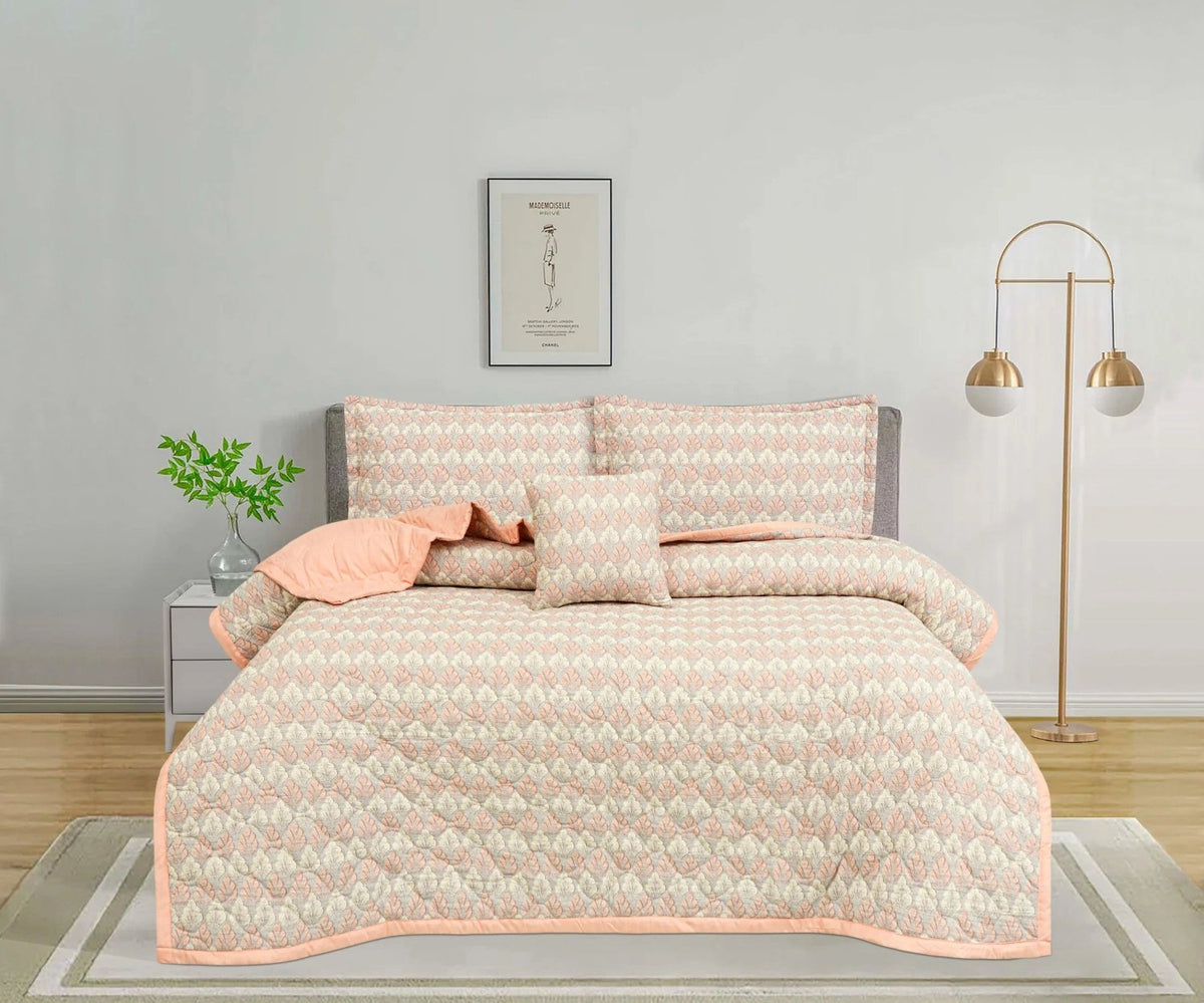 Peach and beige patterned bedspread set with matching pillows on a grey bed